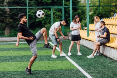 futbol sahasında arkadaşlar, ön planda topu ile adam