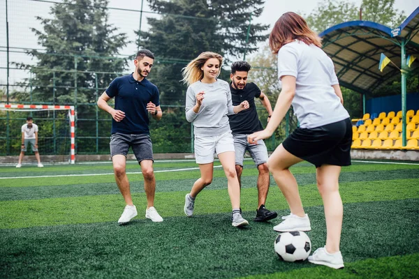 Young men and women playing soccer game outdoors