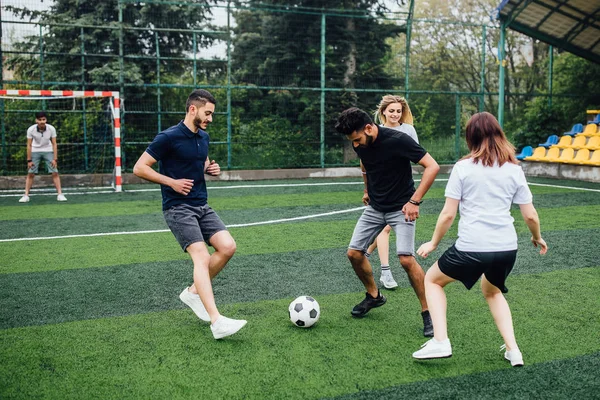 Young men and women playing soccer game outdoors