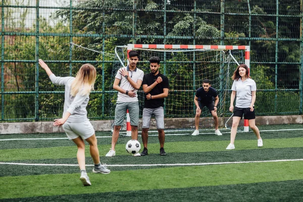 Young men and women playing soccer game outdoors