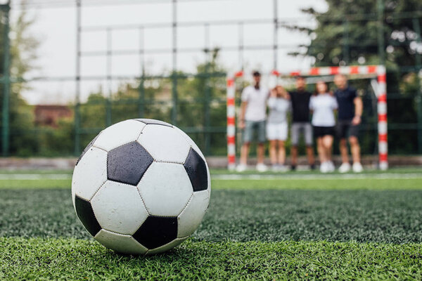 people at stadium, traditional soccer ball in foreground