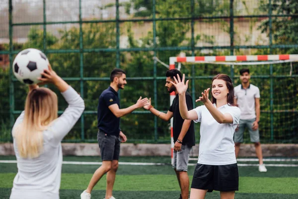 Young men and women playing soccer game outdoors