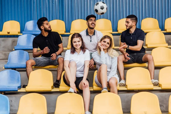 friends sitting on chairs, soccer ball in air, selective focus