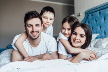 evde yatakta birlikte vakit geçiren aile  