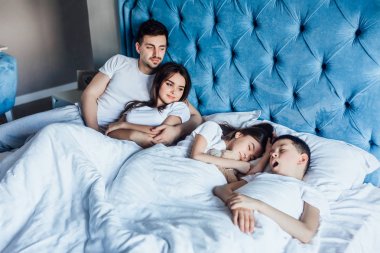 evde yatakta birlikte vakit geçiren aile  
