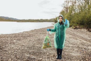 Gönüllü kadın nehir yakınında çöp temizleme 