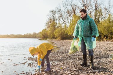 sevimli çocuk göl yakınında çöp temizlemek için baba yardım