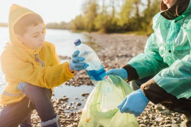 sevimli çocuk göl yakınında çöp temizlemek için baba yardım