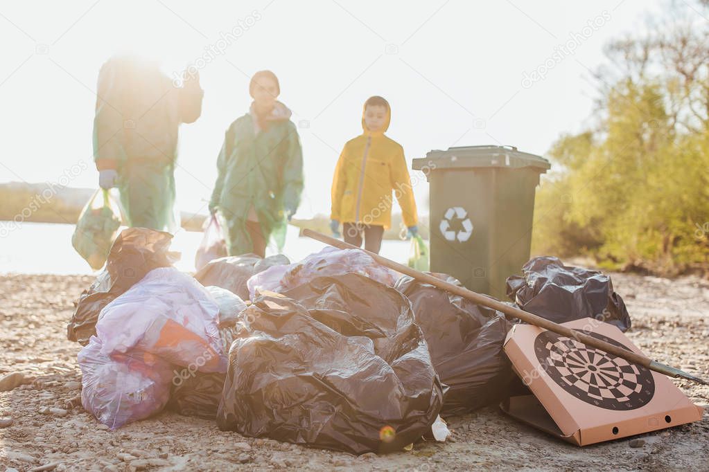 group of volunteers with garbage bags cleaning area near lake