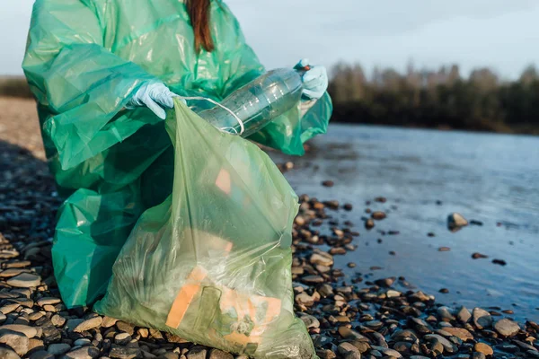 Volunteer female cleaning garbage near river