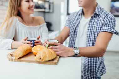 kruvasan ile ahşap masada kahve fincanı, arka planda çift