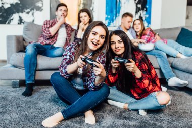 Evde video oyunları oynayan iki genç esmer kadın, seçici odak