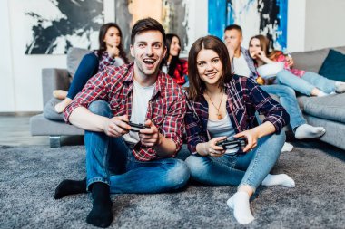 Joystick'leri tutan ve video oyunları oynayan iki mutlu genç arkadaş, seçici odak