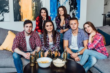 arkadaşlar birlikte kanepede oturan hafta sonu harcama, patlamış mısır yeme ve alkol içme