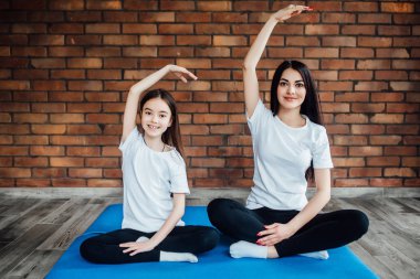 Kadın ve kız evde yoga ve meditasyon yapıyor.