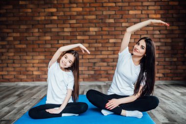 Kadın ve kız evde yoga ve meditasyon yapıyor.