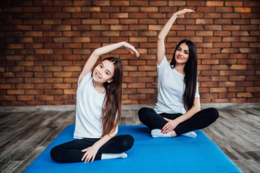 Kadın ve kız evde yoga ve meditasyon yapıyor.
