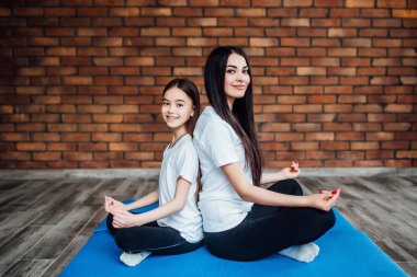 Spor giyim bölümünde kızı olan genç bir kadın yoga yapıyor.