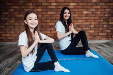 Kadın ve kız evde yoga ve meditasyon yapıyor.