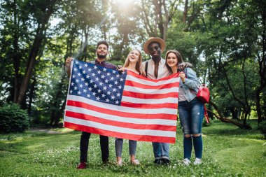 Karma ırk üniversite öğrencileri grubu doğada bir Amerikan bayrağı tutan.