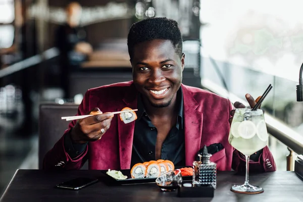Wesoły Kręcone Włosy Afrykański Facet Trzyma Pałeczki Sushi Rolkach Kuchnia — Zdjęcie stockowe