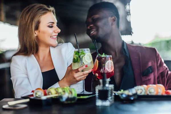 Eating sushi together. Beautiful couple eating sushi while sitting close to each other on the restaurant. Candid emotions.