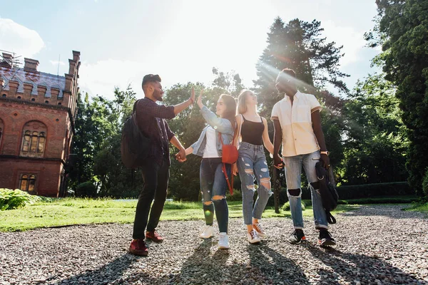 College students walking together outdoors. Group of young people in college campus.