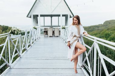 Dağlarda yaz terasında kalan elleri telefon ile çekici, genç bir kadın. Güzellik zamanı.