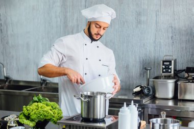 Modern restoran mutfağında yemek hazırlayan şef, İtalyan spagettisinin nasıl pişirildiğini öğretir. Sağlıklı gıda konsepti.