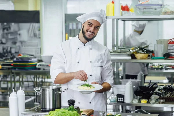 Chef cooking Italian pasta carbonara with cheese parmesan and with dill, and white creamy sauce on kitchen.