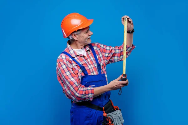 高级建筑工人和水暖工戴着橙色头盔准备工作的专业照片 这些工作与蓝色背景的厘米隔离 — 图库照片