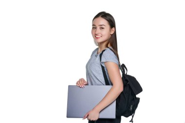 Sırt çantalı genç bir Çinli kadın elinde dizüstü bilgisayarla kameraya bakıyor..