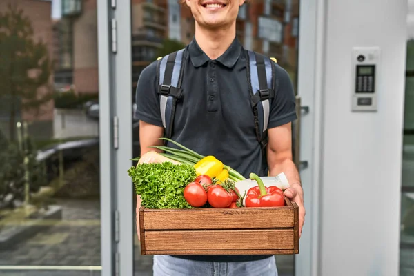 Food and vegetables in the hands of an online courier, close-up. Food delivery around the city.