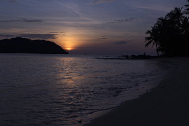 Avuç içi, dağlar ve turuncu gökyüzü güzel manzaralı beach Phu Quoc Adası sae tarafından güzel büyüleyici gün batımı