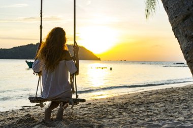 Phu Quoc salıncakta üzerinde kimin oturan ada güzel bir akşam sahilde günbatımı, deniz, tekne ve dağ arayan bir kız silüeti