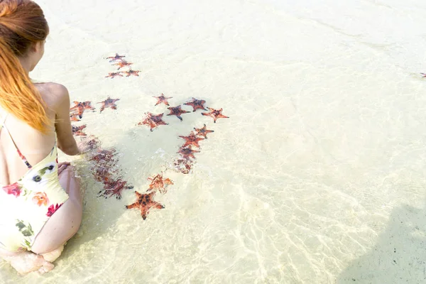 Travel girl with starfishes,making a heart for Valentines Day in honeymoon in Phu Quoc island with clear water and white sand beach