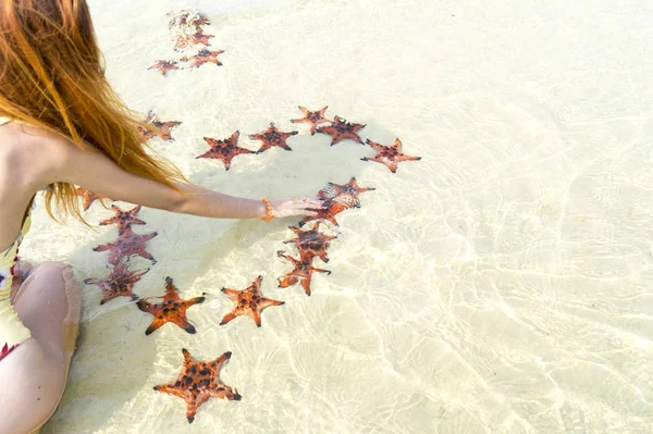 Travel girl with starfishes,making a heart for Valentines Day in honeymoon in Phu Quoc island with clear water and white sand beach