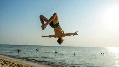 Spor faaliyetleri n plaj. Backflip günbatımı, jimnastik akrobatik blanche, motivasyon içerikli spor exersices yapan genç erkek ile güzel sahilde plaj
