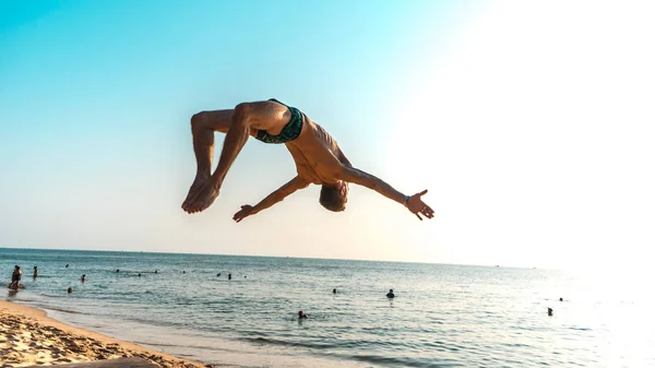 Spor faaliyetleri n plaj. Backflip günbatımı, jimnastik akrobatik blanche, motivasyon içerikli spor exersices yapan genç erkek ile güzel sahilde plaj