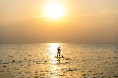 Kürek tahtayı günbatımında Phu Quoc sahilde Vietnam stand, seyahat kavramı, beach etkinlik, alacakaranlıkta güzel gün batımı renklere yatılı kürek kişi ayağa