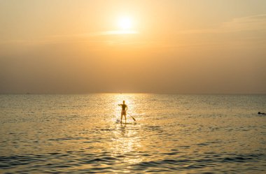 Kürek tahtayı günbatımında Phu Quoc sahilde Vietnam stand, seyahat kavramı, beach etkinlik, alacakaranlıkta güzel gün batımı renklere yatılı kürek kişi ayağa