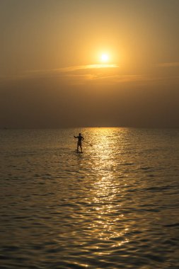 Kürek tahtayı günbatımında Phu Quoc sahilde Vietnam stand, seyahat kavramı, beach etkinlik, alacakaranlıkta güzel gün batımı renklere yatılı kürek kişi ayağa