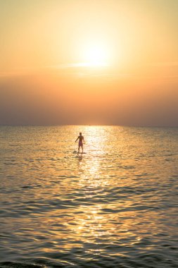 Kürek tahtayı günbatımında Phu Quoc sahilde Vietnam stand, seyahat kavramı, beach etkinlik, alacakaranlıkta güzel gün batımı renklere yatılı kürek kişi ayağa