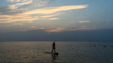 Kürek tahtayı günbatımında Phu Quoc sahilde Vietnam stand, seyahat kavramı, beach etkinlik, alacakaranlıkta güzel gün batımı renklere yatılı kürek kişi ayağa