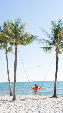 Tatil konsepti. Genç kadın bir plaj salıncak üzerinde salıncak. Phu Quoc plajda mutlu gezgin kadınlar
