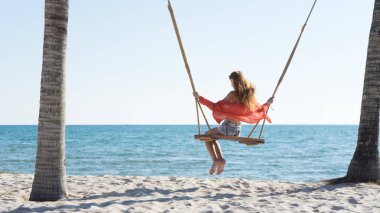 Tatil konsepti. Genç kadın bir plaj salıncak üzerinde salıncak. Phu Quoc plajda mutlu gezgin kadınlar