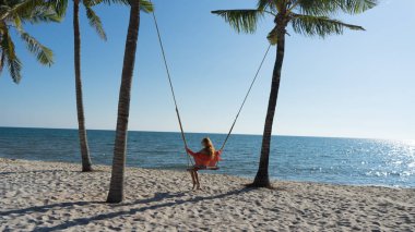 Tatil konsepti. Genç kadın bir plaj salıncak üzerinde salıncak. Phu Quoc plajda mutlu gezgin kadınlar