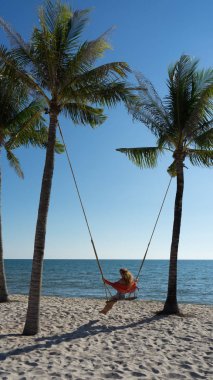 Tatil konsepti. Genç kadın bir plaj salıncak üzerinde salıncak. Phu Quoc plajda mutlu gezgin kadınlar