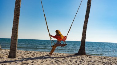 Tatil konsepti. Genç kadın bir plaj salıncak üzerinde salıncak. Phu Quoc plajda mutlu gezgin kadınlar