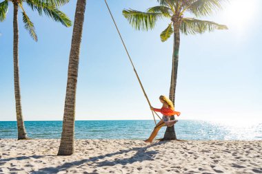 Tatil konsepti. Genç kadın bir plaj salıncak üzerinde salıncak. Phu Quoc plajda mutlu gezgin kadınlar